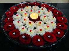 a candle is lit in the center of a wreath made with red and white flowers