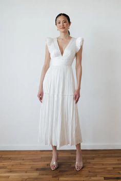 a woman in a white dress standing on a wooden floor