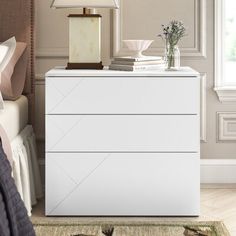 a white chest of drawers sitting next to a lamp on top of a bed in a bedroom