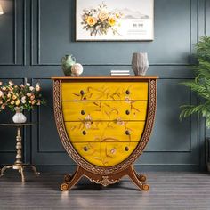 an ornately decorated chest of drawers in a room with blue walls and wooden flooring