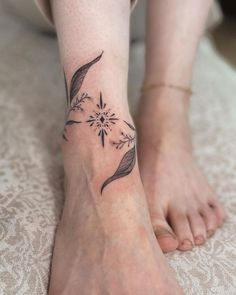 a woman with a tattoo on her foot is sitting on a bed and has one flower in the middle