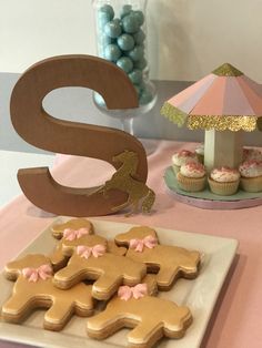 a table topped with cookies and cupcakes next to a wooden letter s sign