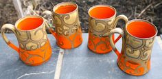 four orange mugs sitting on top of a table