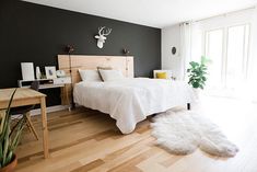 a bed room with a neatly made bed next to a wooden table and chair on top of a hard wood floor