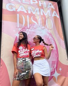 two young women standing next to each other in front of a sign that says aloha gamma disco