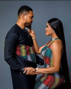 a man and woman standing next to each other in front of a gray background wearing matching outfits