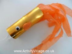 an orange and gold toothbrush with googly eyes on it's end, wrapped in tissue paper