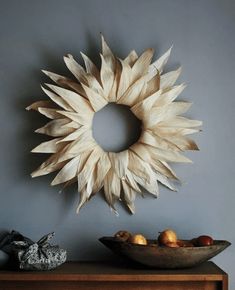 a wooden sunburst hanging on the wall above a bowl of fruit