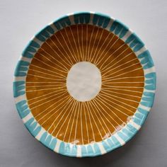 a brown and blue bowl with lines on the bottom is sitting on a white surface