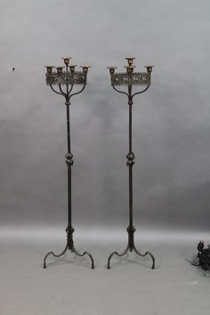 two metal candelabra stands with candles on each one and a small figurine in the middle