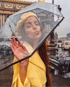 a woman is holding an umbrella in the rain while she's wearing a yellow coat