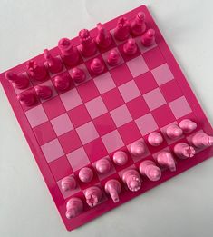 a pink and white checkerboard board with pieces on it