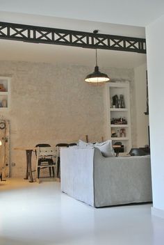 a living room filled with furniture next to a white brick wall and ceiling light fixture