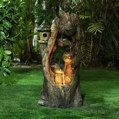 a tree stump that has been carved into a birdhouse with two cats in it