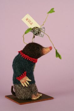 a rat with a tag on it's head is holding a plant in its paws