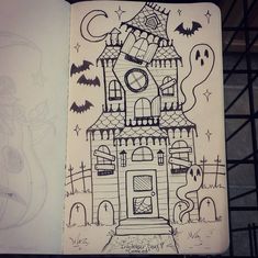 a drawing of a house with bats and ghost faces on the outside, in front of an open notebook