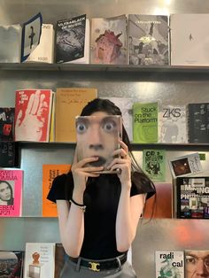 a woman taking a selfie in front of a book shelf with books on it