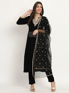 This elegant black velvet set exudes luxury and sophistication. It features intricate hand embroidery and Zardozi work, elevating your look with opulence. Its net dupatta further enhances the royal air of the set, showcasing the artistry of Indian craftsmanship. No. of pieces - 3 piece set. Color - Black. Fabric - Velvet and Net. Kurta Length - 46 inches. Washing Instructions - Dry Clean. Party Velvet Sets With Sheer Dupatta, Festive Velvet Dupatta For Parties, Elegant Black Sharara For Festive Occasions, Festive Party Velvet Dupatta, Black Anarkali Unstitched Chanderi Suit, Elegant Black Sharara With Zari Work, Black Chanderi Anarkali Unstitched Suit, Elegant Black Georgette Sharara, Elegant Black Georgette Set