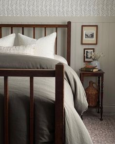 a bed with two pillows on top of it next to a night stand and side table