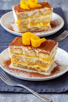 two pieces of cake on white plates with powdered sugar and mango slices in the middle