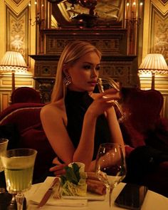 a woman sitting at a table drinking wine