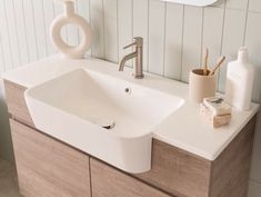 a bathroom sink sitting under a mirror next to a wooden cabinet and white tiled walls