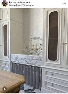 a kitchen with white cabinets and marble counter tops