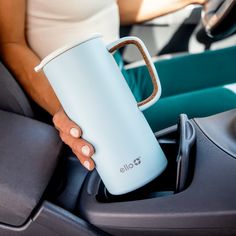 a person holding a coffee cup in their hand while sitting in the back seat of a car