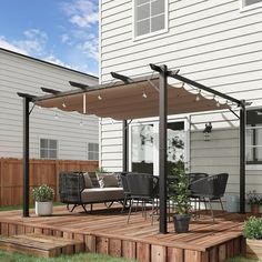 a deck with chairs and table under an awning next to a white house on a sunny day