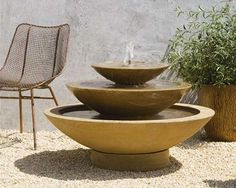 two chairs sitting next to each other in front of a fountain with plants growing out of it