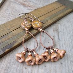 This is an unusual color for me, but I absolutely loved this combination and had to put it together into a pair of earrings. These 12mm bee coin beads are an earthy autumn orange glass with Picasso, gold metallic wash. I combined them with the 6x8mm bell beads. They are a rustic antique copper metallic shimmer over opaque lavender glass. I honestly don't see any lavender glass in these. The tiny beads are a faceted gold colored glass bead. There are also tiny hexagon copper beads. They are 4mm b Handmade Unique Copper Beaded Earrings, Bohemian Copper Beaded Earrings, Autumn Earrings, Amber Bohemian Earrings, Handmade Amber Bohemian Earrings, Rust-colored Bohemian Copper Jewelry, Earthy Earrings, Boho Chic Earrings, Pom Pom Crafts