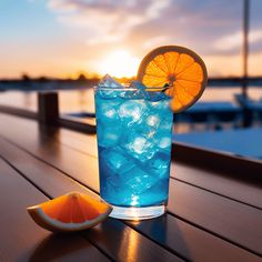 a blue drink with an orange slice sitting on a wooden table next to the water