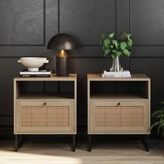 two nightstands with plants and books on them in front of a black painted wall