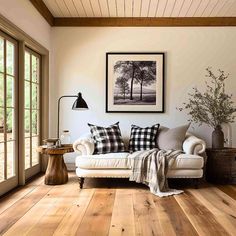 a living room with wood floors and white furniture in the center, framed pictures on the wall