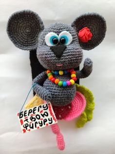 a crocheted mouse is holding a sign