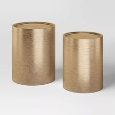 two gold vases sitting next to each other on a white surface with no one around them