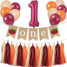 the first birthday banner is decorated with balloons and tassels