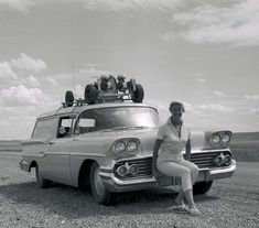 a woman sitting on the hood of an old car