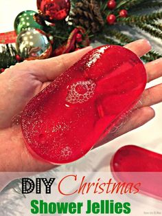 a hand holding a red soap in front of a christmas tree with the words diy christmas shower jellies on it