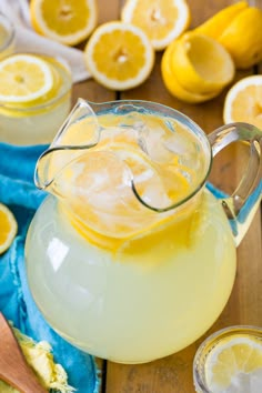 a pitcher filled with lemonade sitting on top of a table next to sliced lemons