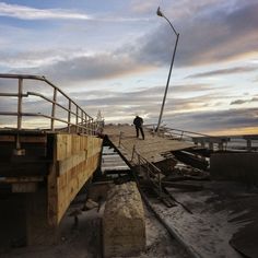 a man standing on top of a wooden bridge