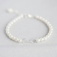 A delicate pearl bracelet with a sterling silver infinity symbol as its focal piece.This bracelet would make a wonderful gift for any occasion or a lovely treat for yourself. Also perfect as a gift for your bridesmaids to wear on your special day and long afterwards, as a symbol of a unique friendship.This item is lovingly handmade to order just for you in the Corrine Smith workshop.Presented in an organza bag with the sentiment card of your choice, ready to give or keep.If you would like to upg Tattoos Infinity, Tattoos Skull, Bridesmaid Pearls, Adjustable Jewelry, Wedding Jewelry Bracelets, Bridesmaid Bracelet, Infinity Symbol, Dainty Bracelets, Swarovski Pearls