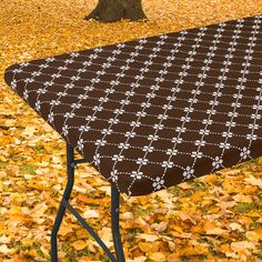 an ironing board on top of a table covered in leaves next to a tree