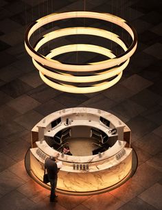 a man standing in front of a circular light fixture on the floor next to a counter