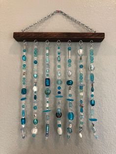 a wind chime hanging on the wall with beads and shells attached to it's chain