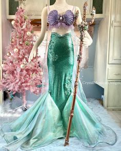 a mannequin dressed as a mermaid with a cane in front of a pink christmas tree