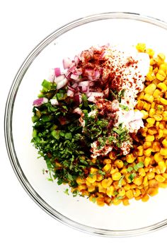 a bowl filled with corn and seasoning next to other ingredients on a white surface