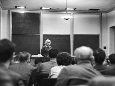 a woman standing in front of a class room full of people