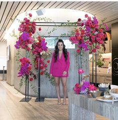 a woman in a pink dress standing next to flowers