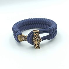 a blue rope bracelet with an ornate gold cross on it's end and a black cord